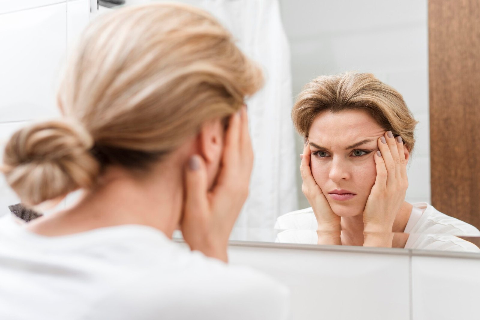 woman-holding-her-face-looking-mirror